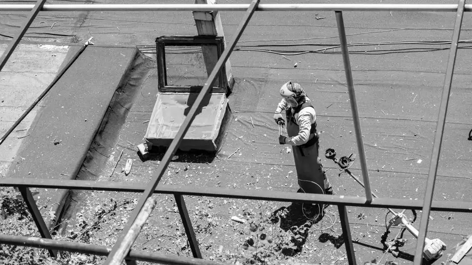 A lone professional worker on a rooftop, captured from above, busy with repairs.