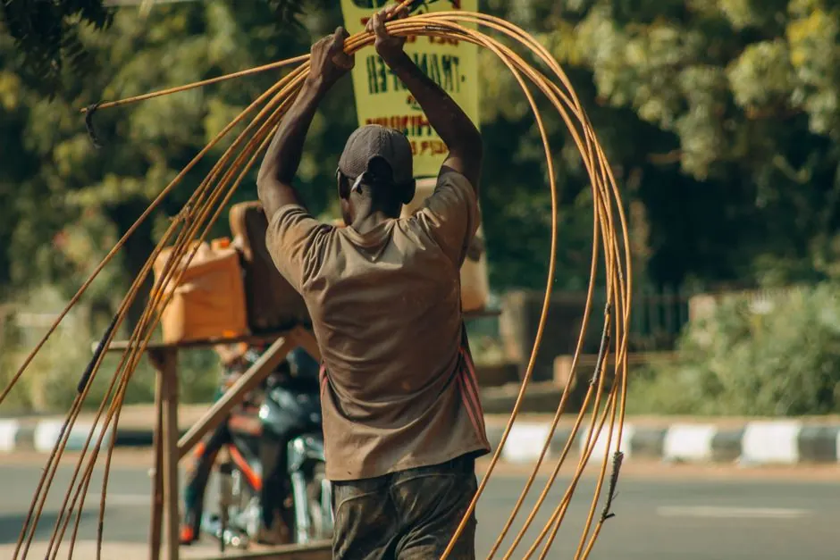 Rear view of a worker managing electrical wires on a roadside. Urban outdoor setting.